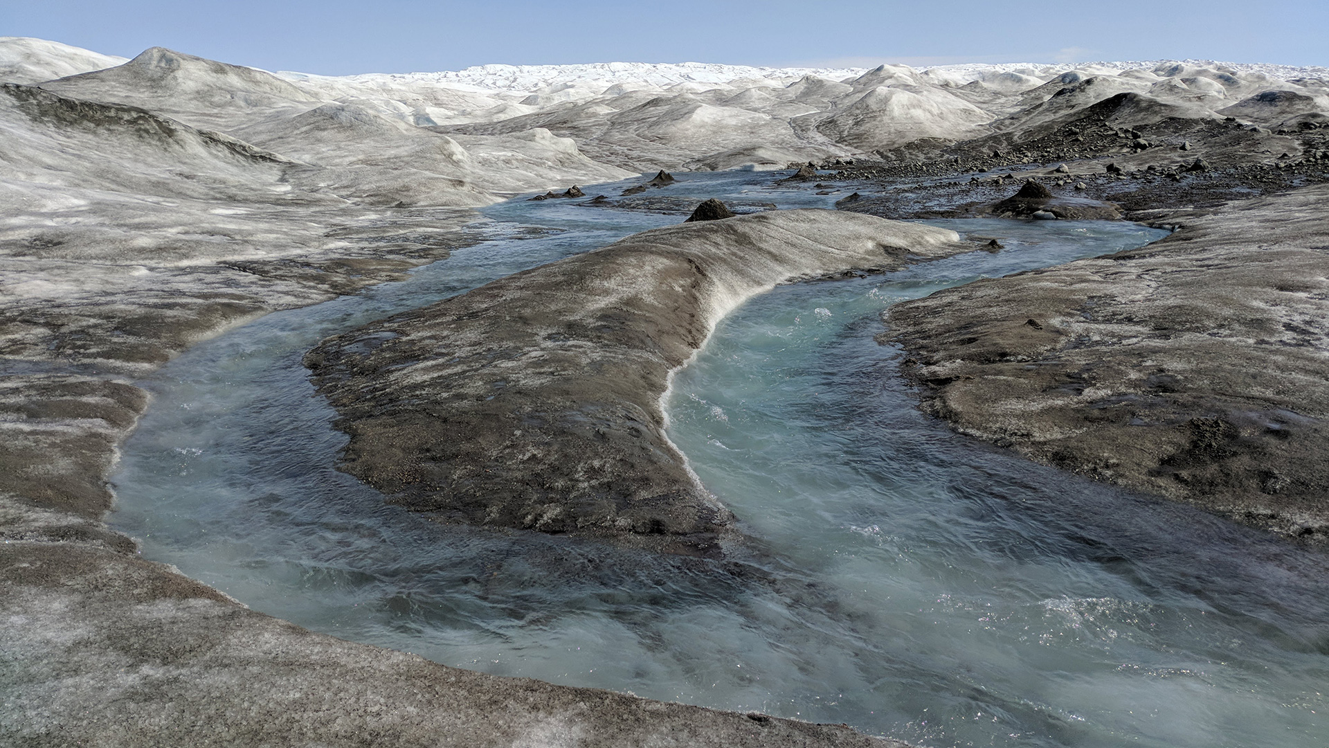 Canaux d'eau de fonte à la surface du glacier Russell au Groenland. Le matériau sombre est un mélange de saleté soufflée par le vent et de matière microbienne qui peut accélérer la fonte de la glace.