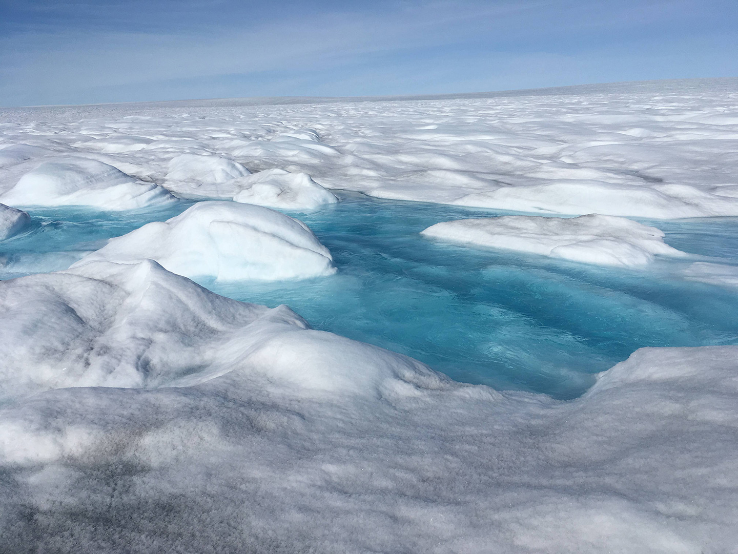 Bassins d'eau de fonte de surface à Sermeq Kujalleq au Groenland. Cette eau de fonte va se frayer un chemin jusqu'au fond de la glace à travers un réseau de fissures, crevasses et moulins.